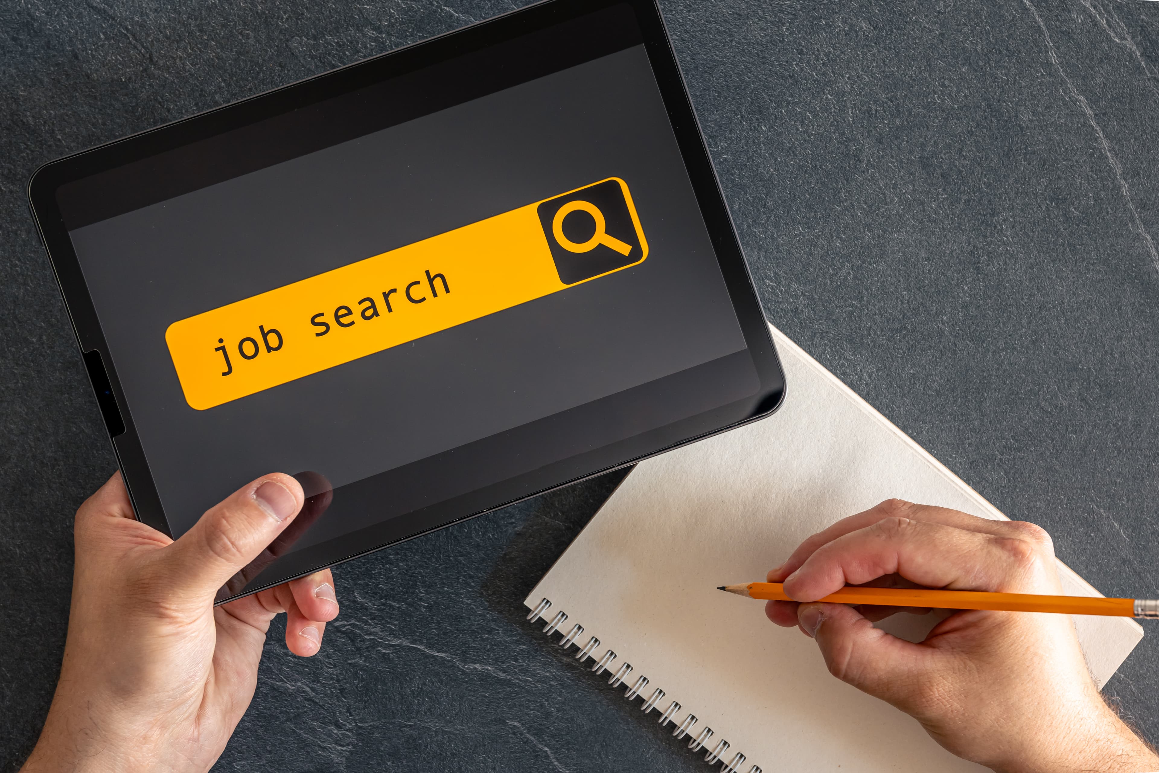 Hands holding a tablet showing a job search